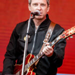 Noel Gallagher tocando guitarra no palco