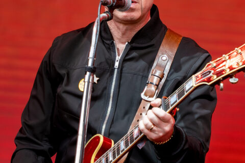 Noel Gallagher tocando guitarra no palco